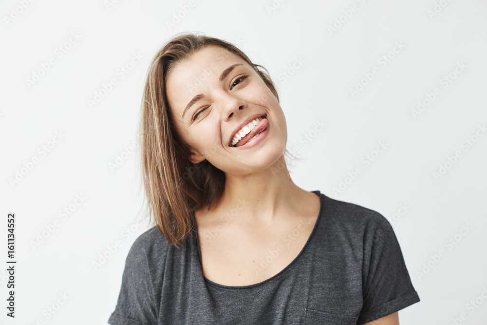 Funny cute young girl smiling winking showing tongue looking at camera over white background. Funny cute young girl smiling winking showing tongue looking at camera over white background.