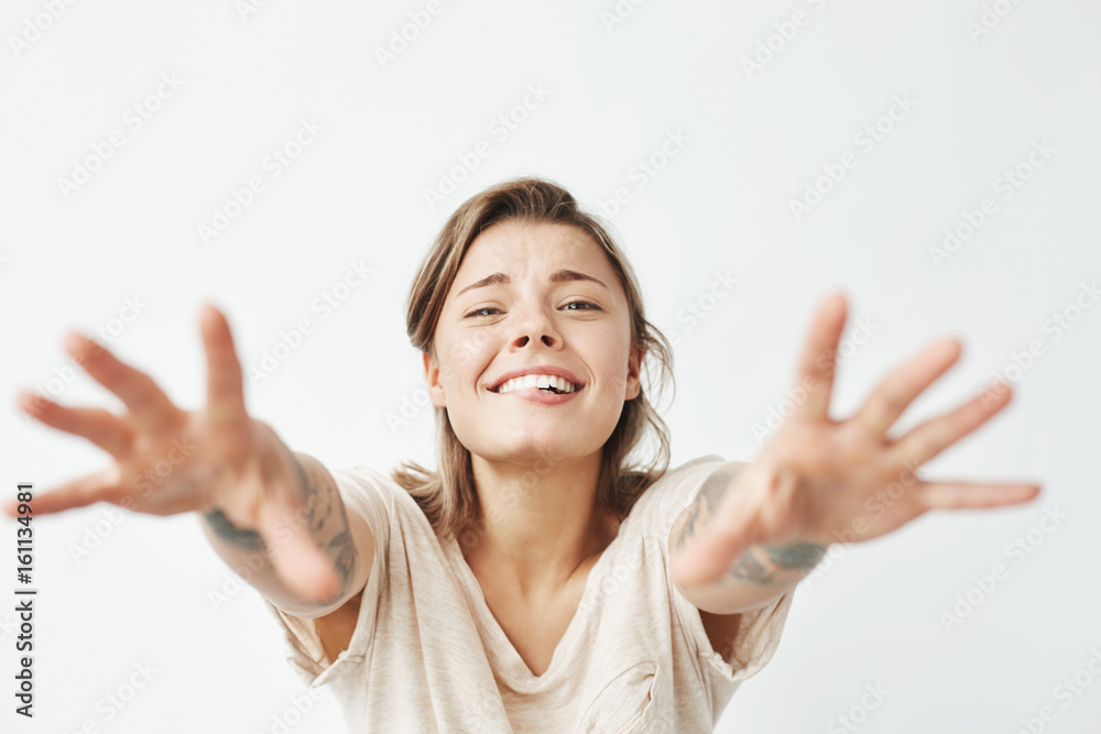 Young funny pretty girl smiling stretching hands to camera over white background. Young funny pretty girl smiling stretching hands to camera over white background.