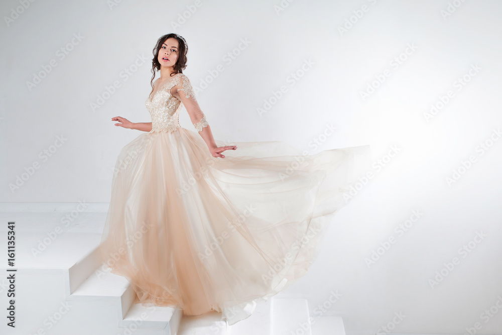 Portrait of a beautiful girl in a wedding dress. Bride in a luxurious dress standing on the stairs, climb up Portrait of a beautiful girl in a wedding dress. Bride in a luxurious dress standing on the stairs, climb up