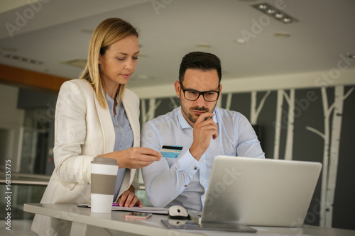 Wallpaper Mural Two business people sitting on office and using credit card. Business people checking credit card on laptop. Torontodigital.ca