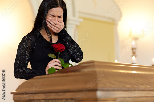 crying woman with red rose and coffin at funeral