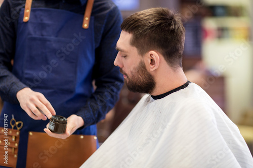 barber showing hair styling wax to male customer