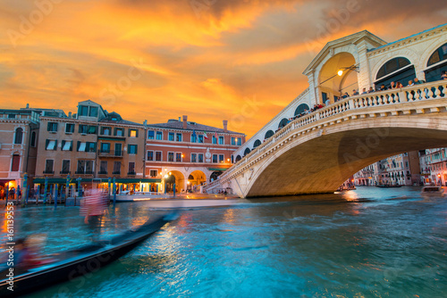 Bright charming landscape with gondola and  Rialto Bridge at sunset in Venice, Italy, Europe