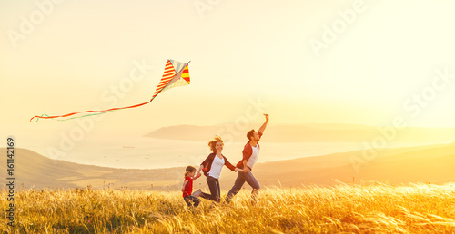 Happy family father of mother and child daughter launch a kite on nature at sunset