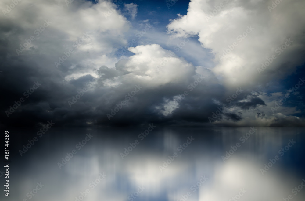 Obraz premium Blue sky. Dramatic clouds over sea. Blurred reflection of sky in water