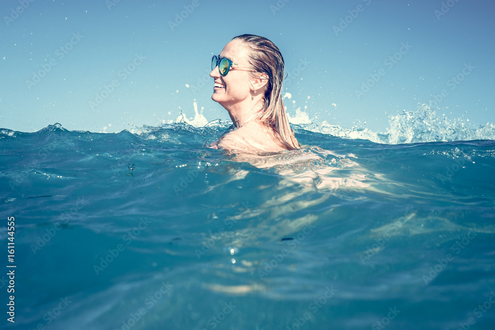 Beautiful young sexy woman enjoying swimming in refreshing sea water. Bali island.
