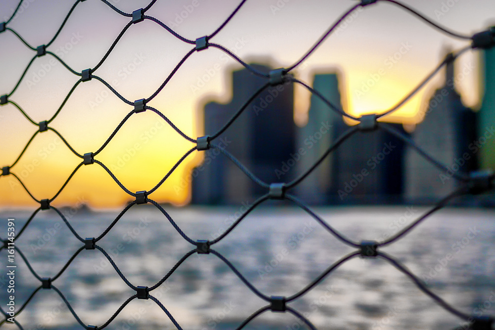 Sunset in Downtown Manhattan in New York City from behind link fence barrier Sunset in Downtown Manhattan in New York City from behind link fence barrier