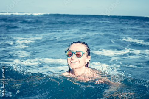 Beautiful young sexy woman enjoying swimming in refreshing sea water. Bali island.