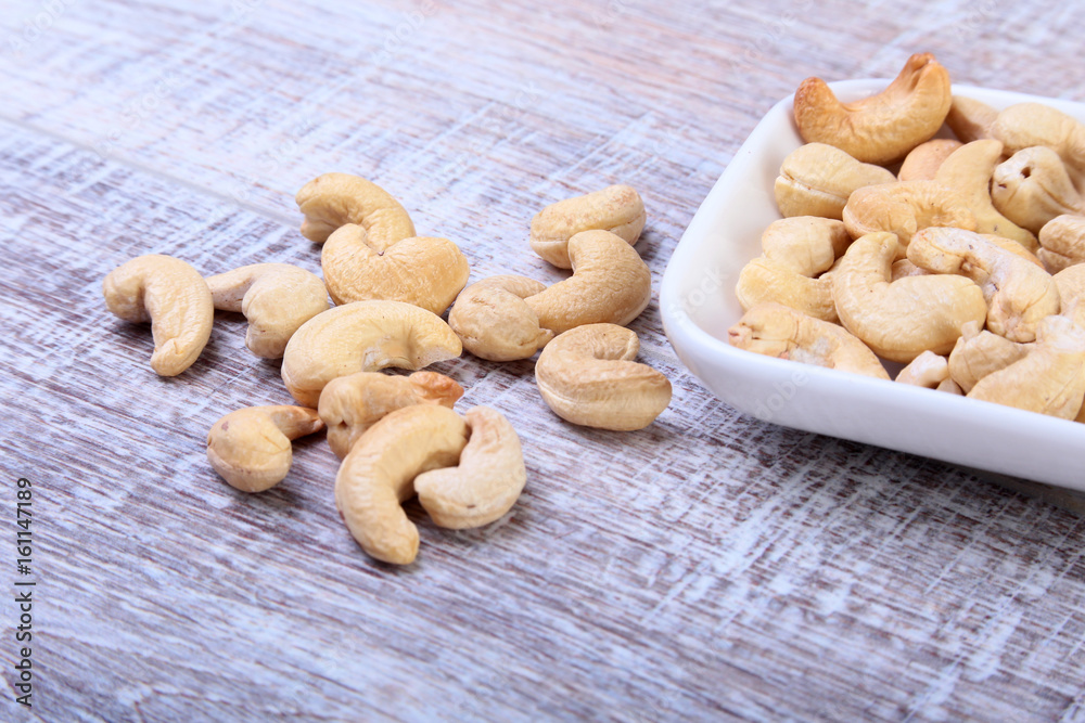 nuts cashews in white bowl on wooden background. Selective focus. nuts cashews in white bowl on wooden background. Selective focus.