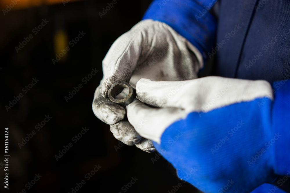 Man wearing a pair of protection gloves looking at a piece of steel.