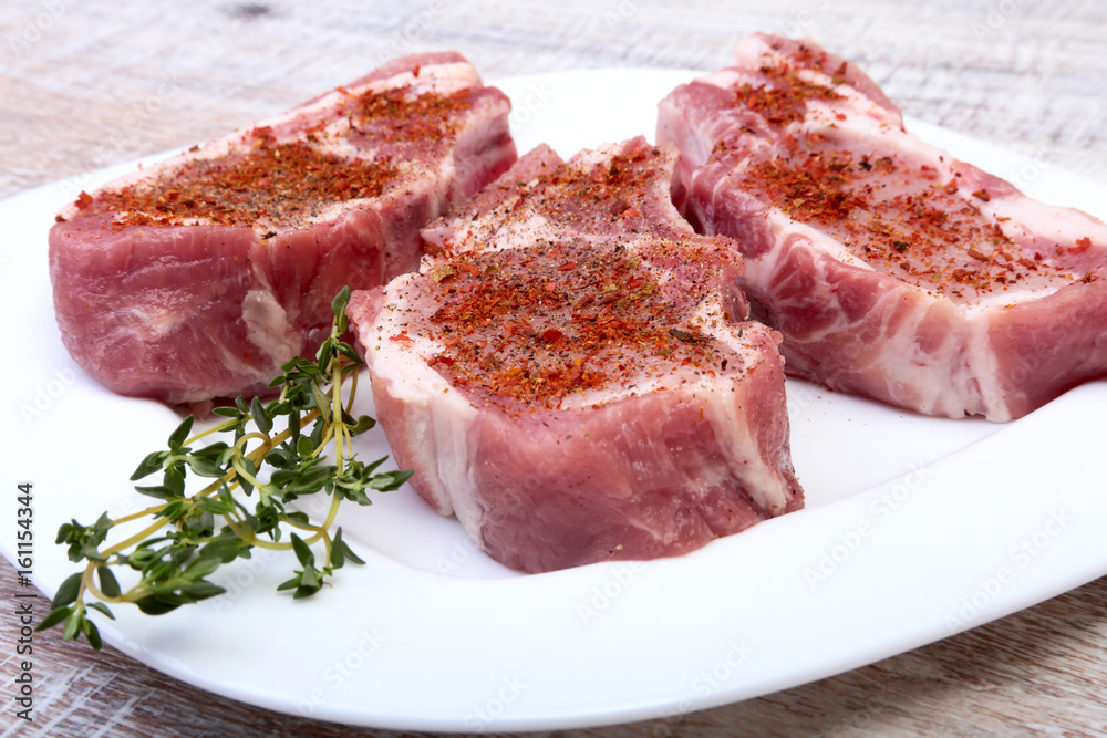 Raw pork chops, spices and rosemary on cutting board. Ready for cooking.