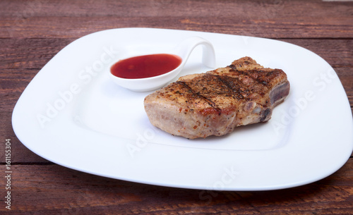grilled pork chop with Cranberry sauce on plate on wooden board