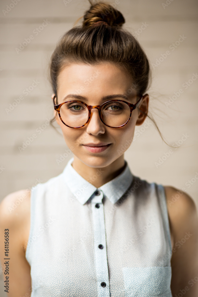 Close up portrait of beautiful hipster woman in trendy glasses looking to the camera. Gorgeous pretty sexy girl in eyeglasses. White urban wall background. Business, active, freedom lifestyle concept.