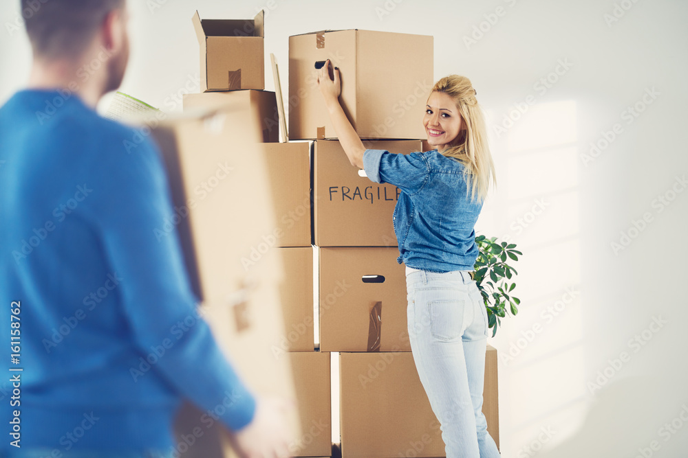 Obraz premium Young Caucasian woman relocating boxes, lots of boxes around