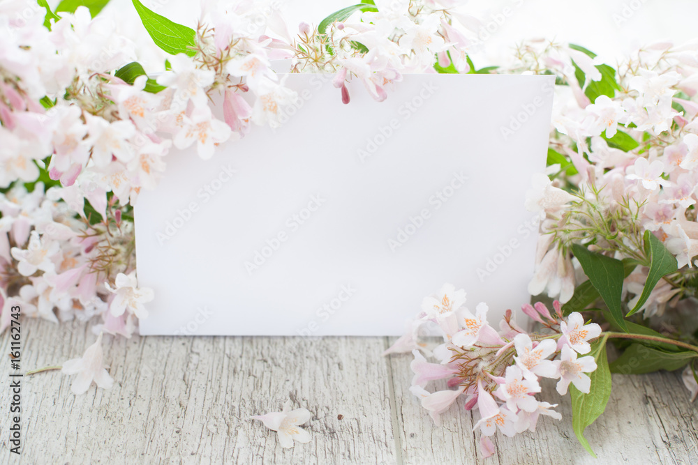 Mockup- flowers, peonies on a wooden table, white card. Woman's desk.