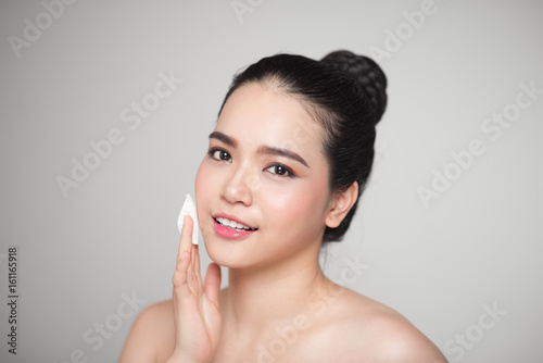 Happy smiling beautiful asian woman using cotton pad cleaning skin.