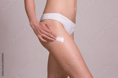 Close up of a perfect female legs. Woman applying moisturizer. © anidimi