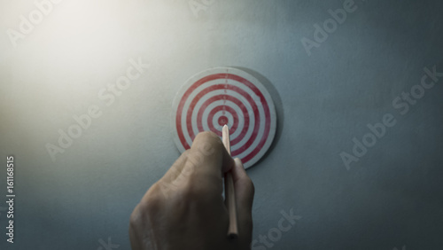 part of man's hand while aiming pencil to dart board