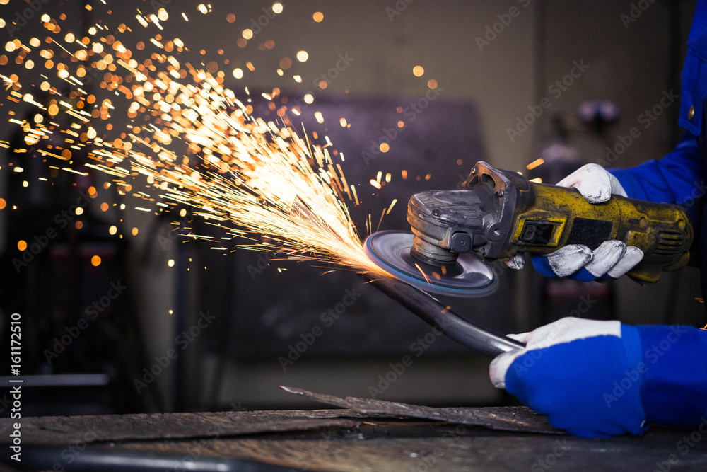 Grinding a piece of metal pipe and producing sparks.