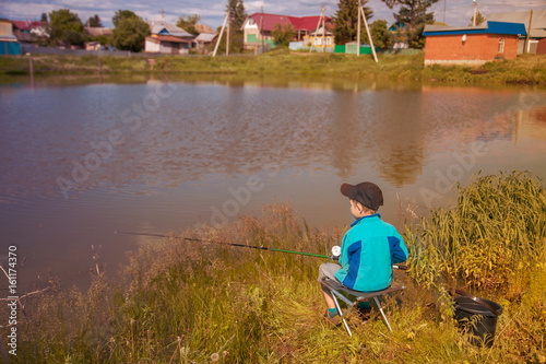 boy fisherman holding a fishing rod on the lake