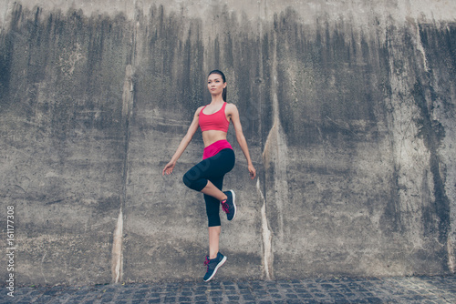 Fitness sport woman in fashion sport wear is jumping in the city street on the grey concrete background. Outdoors sports clothing and shoes, urban style