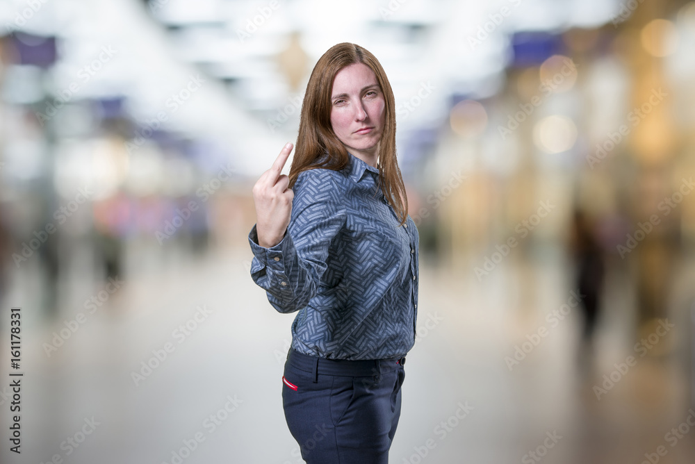 Pretty young business woman giving flipping the bird over blur background