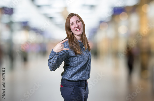 Pretty young business woman making horn gesture over blur background