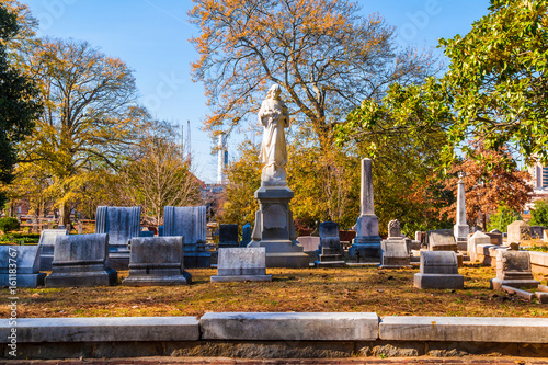 Group of tombstones and sculpture of Virgin Mary on the Oakland Cemetery in sunny autumn day, Atlanta, USA photo