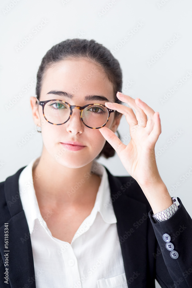 Confident young businesswoman touching glasses