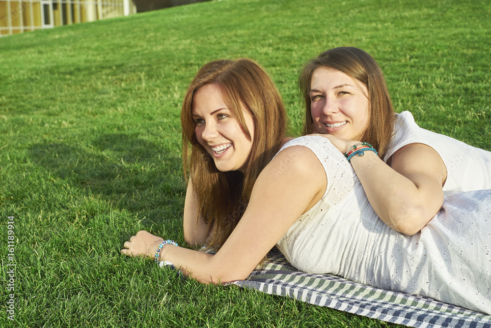two girlfriends lying on the lawn two girlfriends lying on the lawn