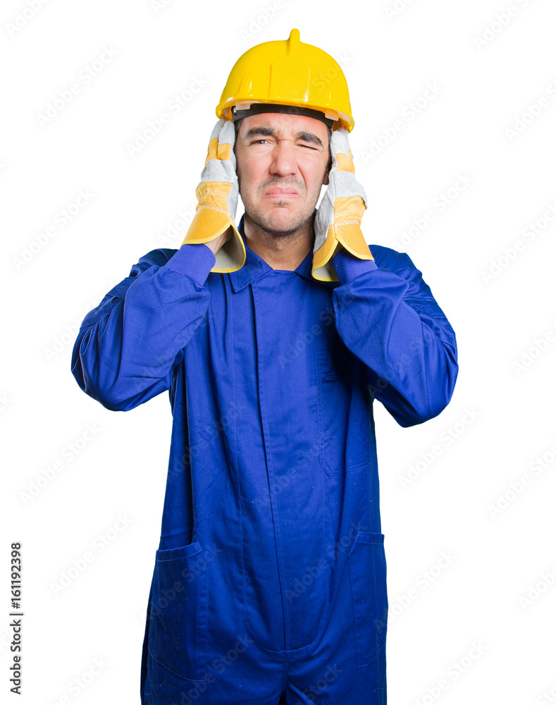 Worried workman covering his ears with his hands on white background