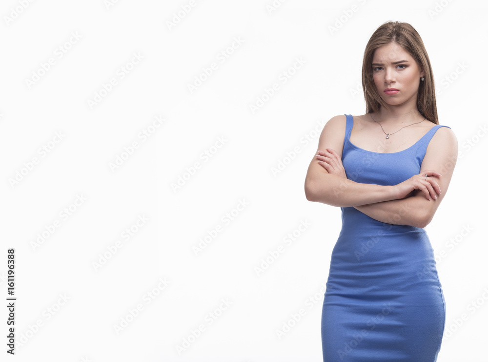 Young offended woman in a blue dress on a gray background. Ideal for banners, registration forms, presentation, landings, presenting concept.