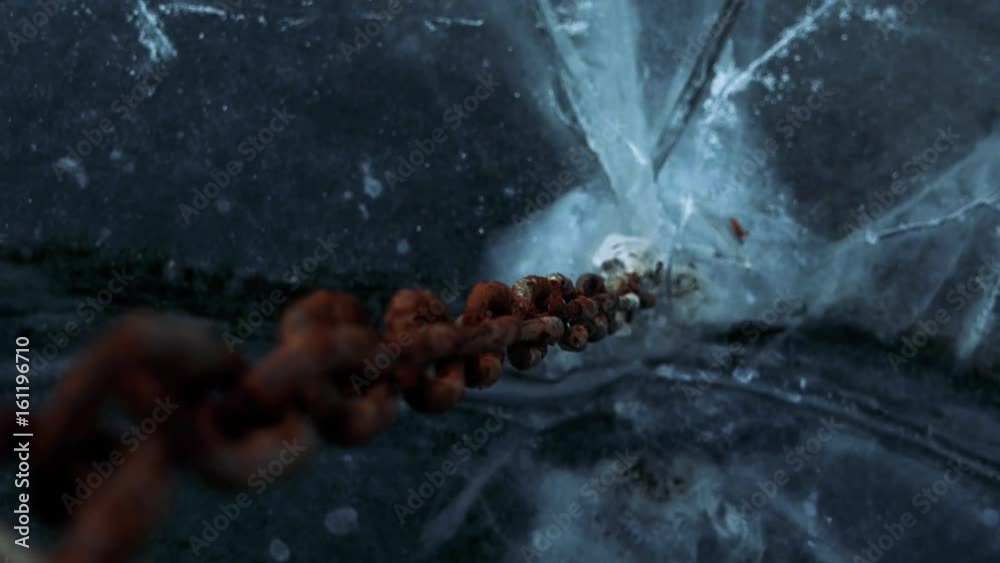 A closeup from the top on a rusty chain stuck in a frozen river