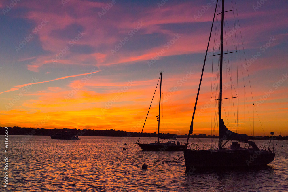 Epic and beautiful sunset over harbor with sailboat silouettes