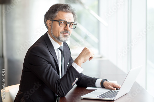 Intelligent handsome man with laptop in cafe
