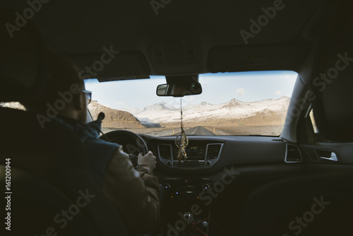 Young attractive man (tourist) driving a car in the mountains