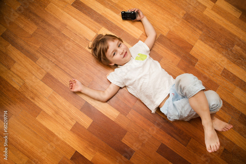 little boy lies on a floor and plays with toy car 