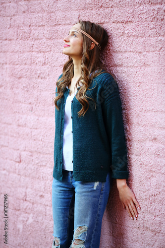 Fairy positive beautiful woman standing near pink brick wall, street style, lifestyle, with wicker headband