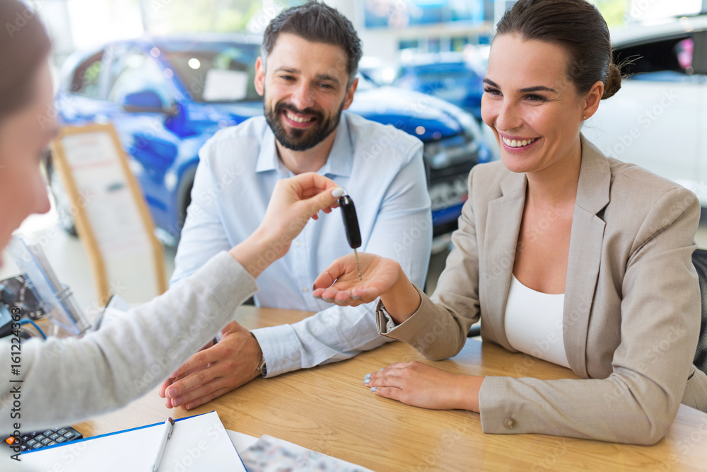 Young couple with car dealer in auto salon
Young couple with car dealer in auto salon