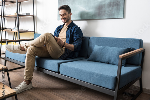 Εκτύπωση καμβά Joyful youthful guy with beard relaxing in sitting-room