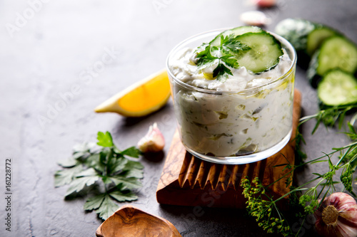 Tzatziki Traditional Greek sauce with ingredients cucumber, garlic, parsley, lemon, mint. Food Background.Snack, Meze in a glass cup.Copy space for Text.selective focus.