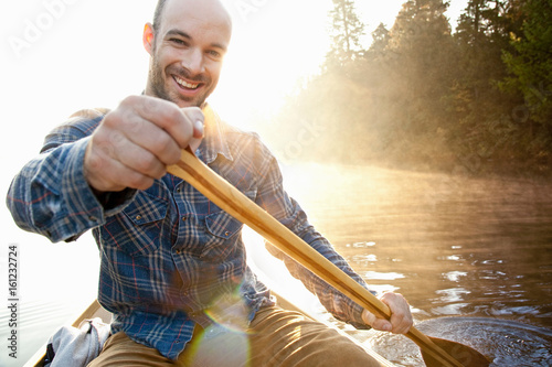 Man rowing canoe in still lake photo