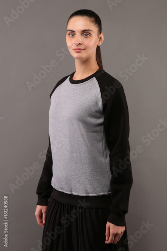 Young hipster girl wearing blank grey and black cotton sweatshirt with crew neck and raglan sleeves with copy space for your design or logo, mock-up of ltemplate womens hoodie photo