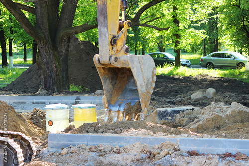 Foto Excavator digs to plastic tank gas oil catcher in the ground during the construction of a car park for tourist buses, Russia