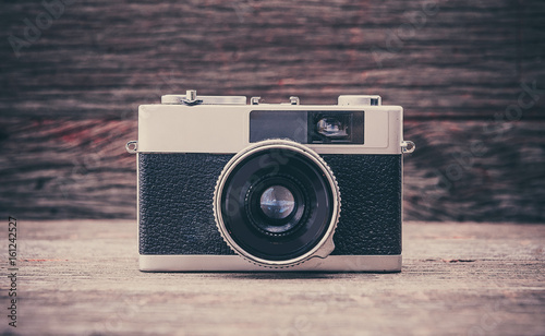 Retro film photo camera on wooden background.