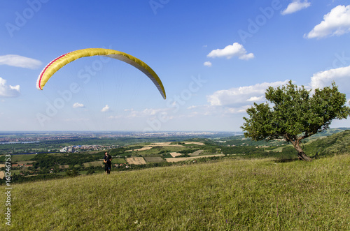 Man with paraglider preparing for flight, on hill beautiful clouds 