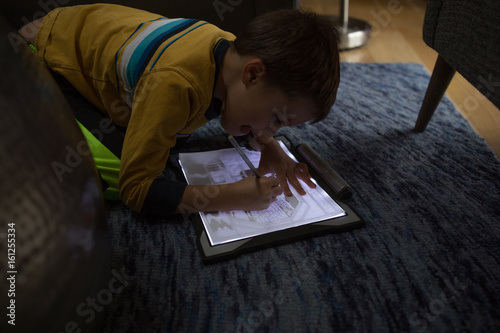 Young boy kneeling on floor, tracing image onto paper