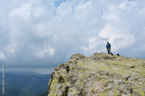 Elderly man takes photos with his camera on tripod high on the rocks of Belintash - an ancient Thracian sanctuary with stellar map dedicated to god Sabazios - Dionysus  Rhodope Mountain  Bulgaria