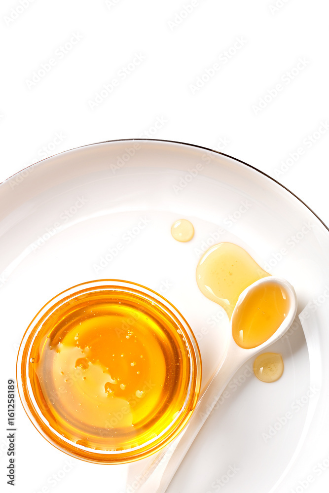 Honey in a little bowl with a spoon. White background. Top view