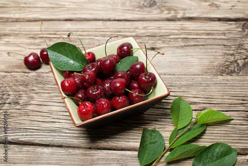 Fresh cherries in a square ceramic dish on wooden background 